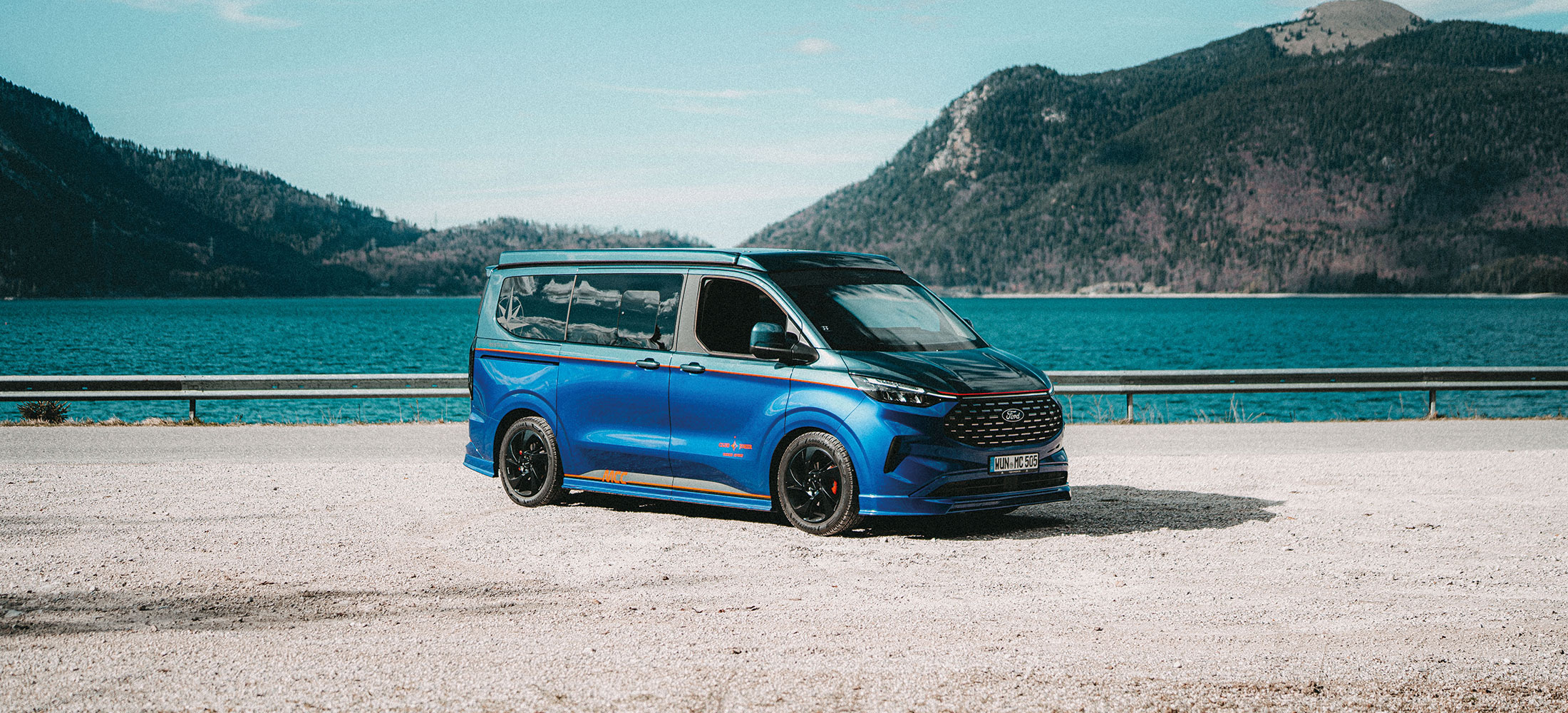 Ford Nugget auf Strand mit Meer im Hintergrund