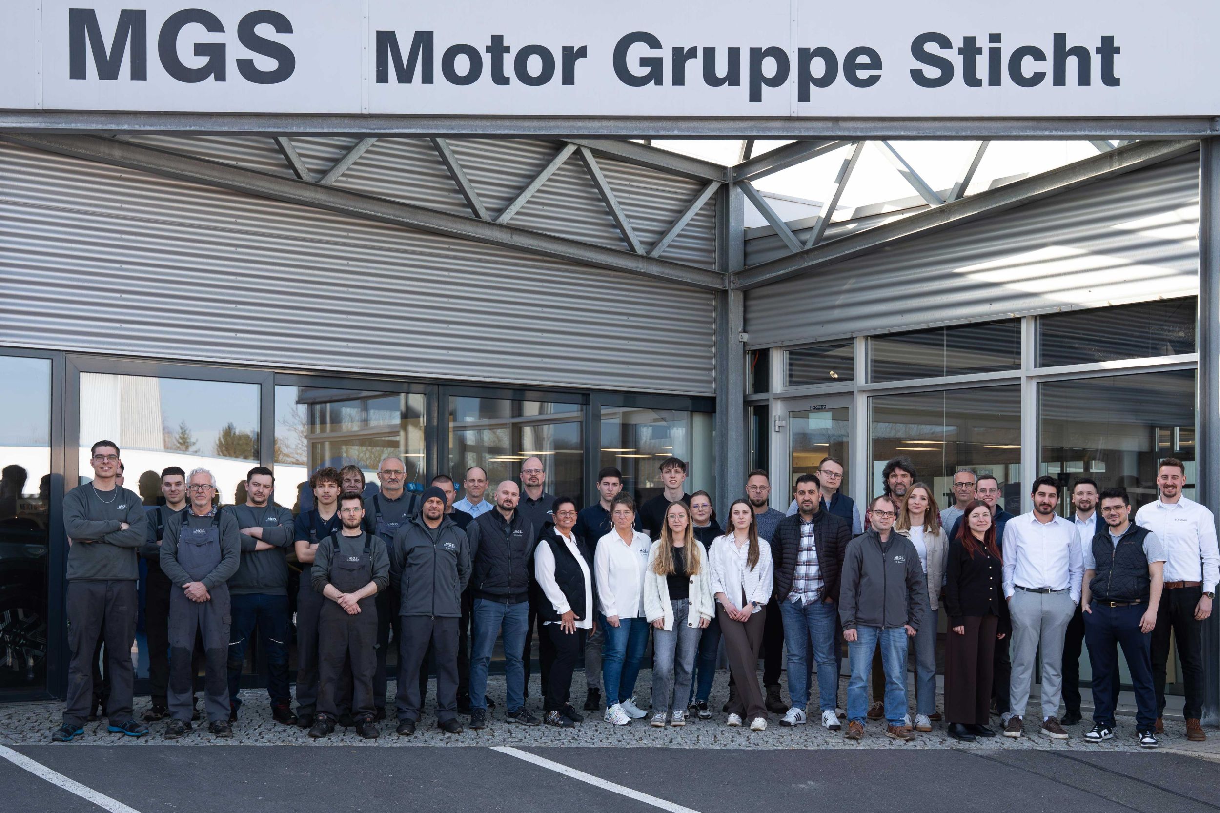 Gruppenfoto des Teams der MGS Motor Gruppe Sticht am Standort Wunsiedel vor dem Autohaus-Eingang.
